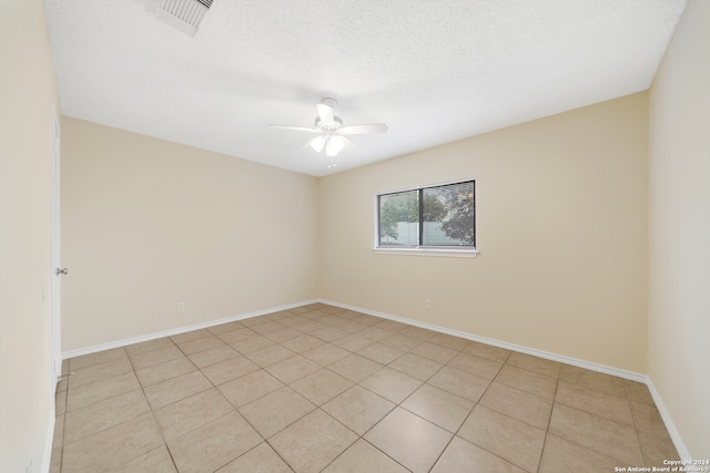 empty room with a textured ceiling, light tile patterned floors, and ceiling fan