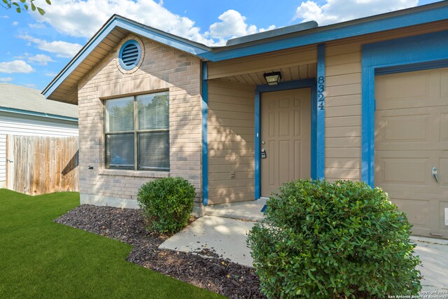 entrance to property featuring a garage and a lawn