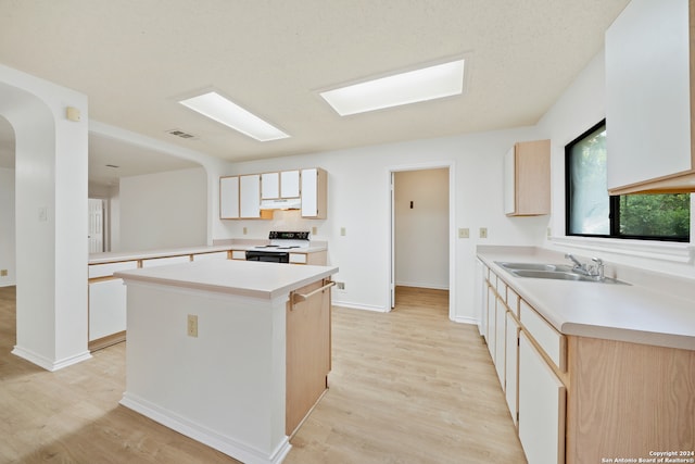 kitchen with electric stove, kitchen peninsula, sink, a kitchen island, and light wood-type flooring