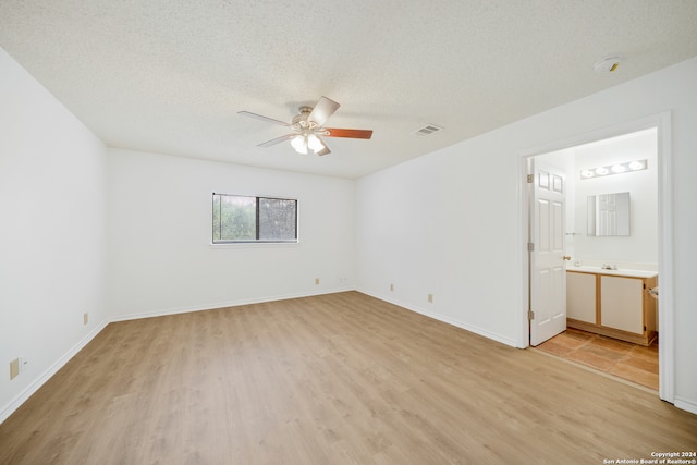 unfurnished bedroom with ensuite bathroom, ceiling fan, a textured ceiling, and light wood-type flooring