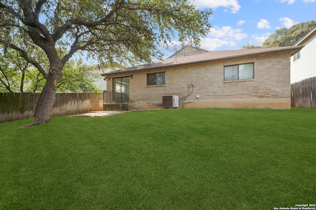 back of property with central AC unit, a patio, and a lawn