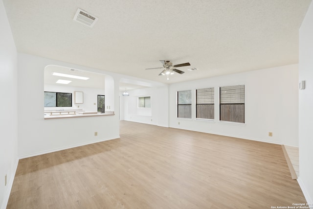 unfurnished living room with a textured ceiling, ceiling fan, and light hardwood / wood-style flooring