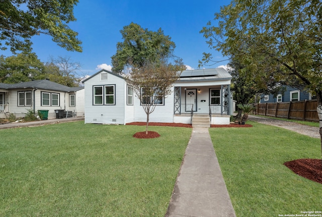 bungalow-style home with solar panels, covered porch, and a front lawn