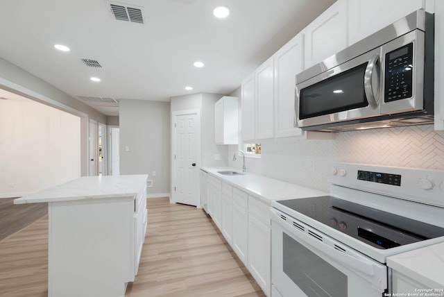 kitchen with light stone countertops, white cabinetry, white electric stove, and light hardwood / wood-style flooring