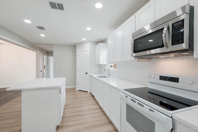 307 Bexar Dr, San Antonio, TX 78228 - kitchen featuring stainless steel microwave, white electric stove, a kitchen island, recessed lighting, and light wood-type flooring