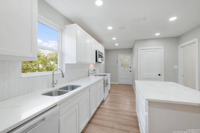 kitchen featuring light hardwood / wood-style floors, white cabinets, sink, backsplash, and white appliances