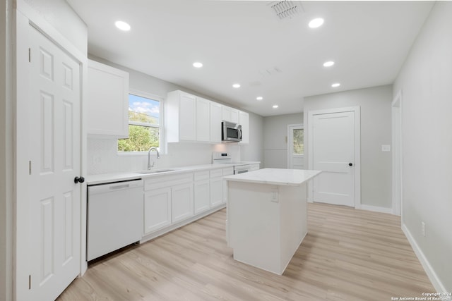 kitchen with white cabinets, light wood-type flooring, white appliances, and a kitchen island