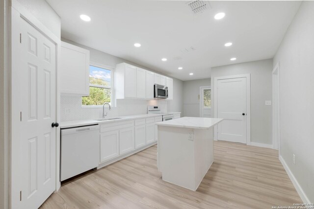 307 Bexar Dr, San Antonio, TX 78228 - kitchen with white appliances, a sink, a kitchen island, white cabinetry, and recessed lighting