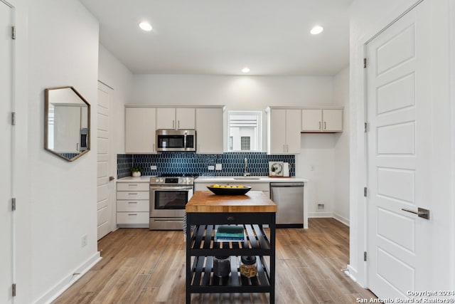 kitchen with stainless steel appliances, sink, light wood-type flooring, and decorative backsplash