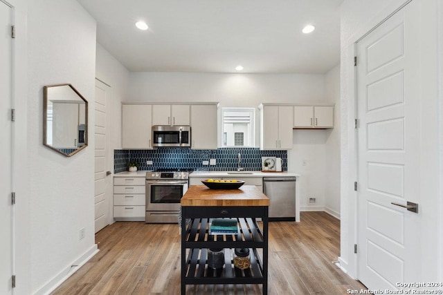 3214 N Elmendorf St, San Antonio, TX 78201 - kitchen featuring stainless steel appliances, light countertops, backsplash, white cabinets, and a sink