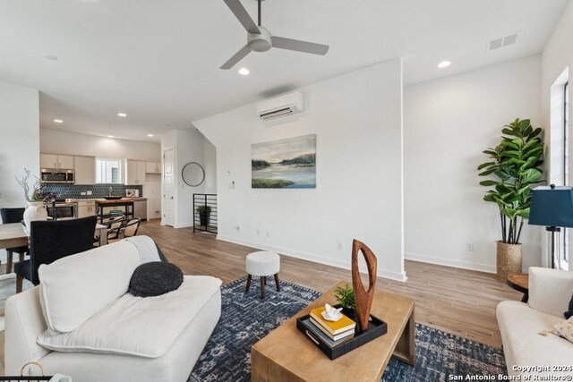 living room featuring ceiling fan, light hardwood / wood-style floors, and a wall mounted AC