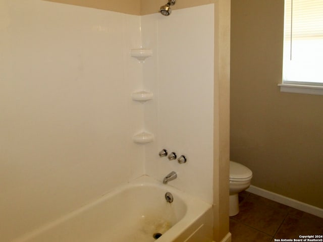 bathroom with tile patterned floors, washtub / shower combination, and toilet