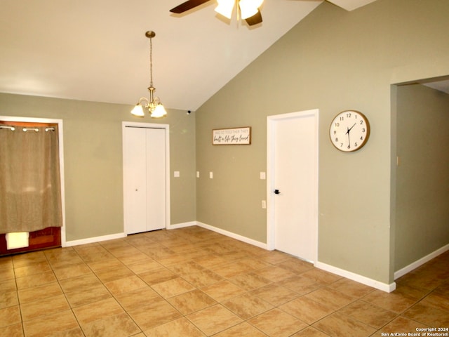 tiled empty room featuring ceiling fan with notable chandelier and high vaulted ceiling