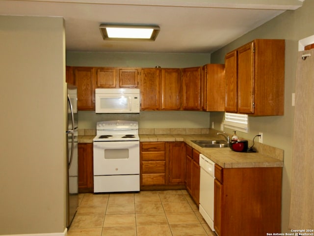 kitchen with white appliances, sink, and light tile patterned floors