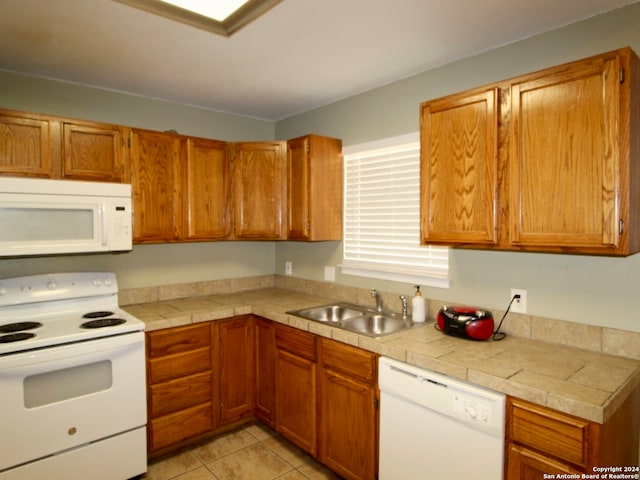 kitchen with light tile patterned flooring, white appliances, tile countertops, and sink