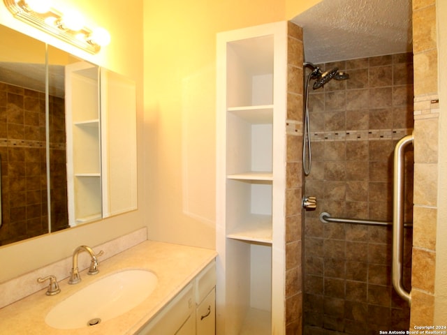 bathroom with a tile shower and vanity