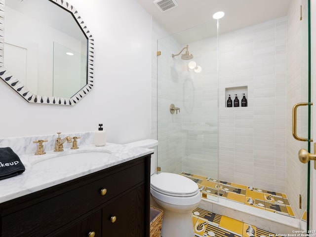 bathroom with toilet, vanity, and a shower with shower door