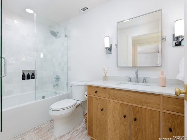 full bathroom with enclosed tub / shower combo, vanity, and toilet