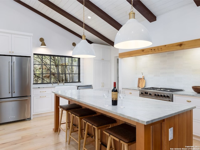 kitchen with hanging light fixtures, a large island, high quality appliances, and white cabinetry