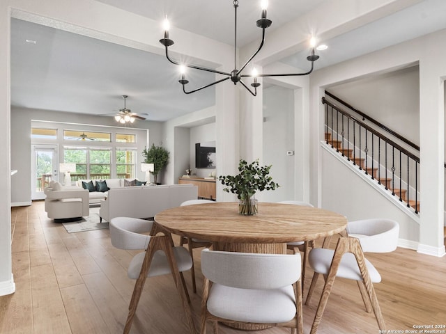 dining room featuring ceiling fan with notable chandelier and light hardwood / wood-style flooring