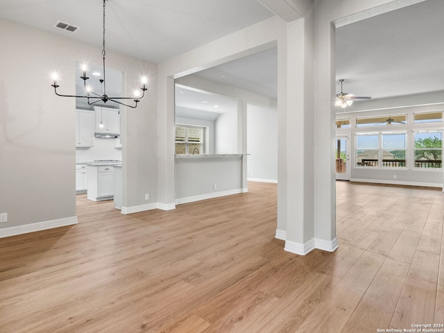 unfurnished dining area featuring light hardwood / wood-style floors and ceiling fan with notable chandelier