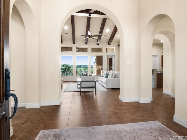 tiled living room featuring a towering ceiling, ceiling fan, and beam ceiling