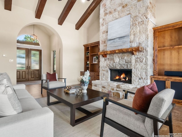 living room featuring french doors, high vaulted ceiling, a fireplace, and beam ceiling