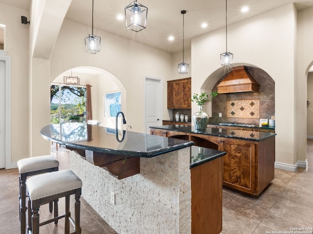 kitchen with a kitchen island with sink, a towering ceiling, and decorative light fixtures