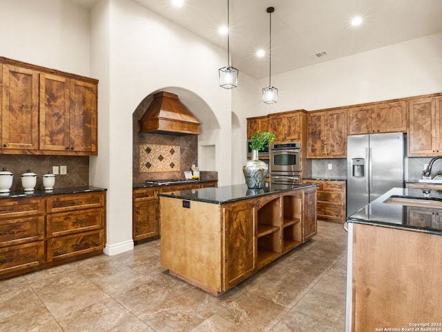 kitchen with stainless steel appliances, a center island with sink, a towering ceiling, sink, and pendant lighting