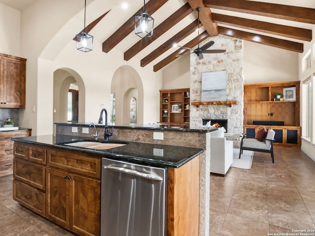 kitchen featuring a center island with sink, sink, decorative light fixtures, a fireplace, and dishwasher