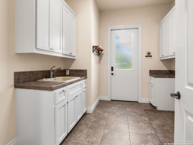 clothes washing area featuring light tile patterned floors and sink