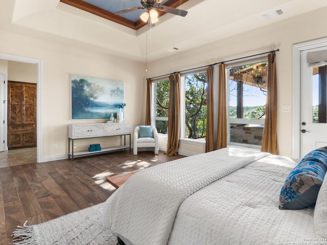 bedroom with ceiling fan, dark hardwood / wood-style floors, and a tray ceiling