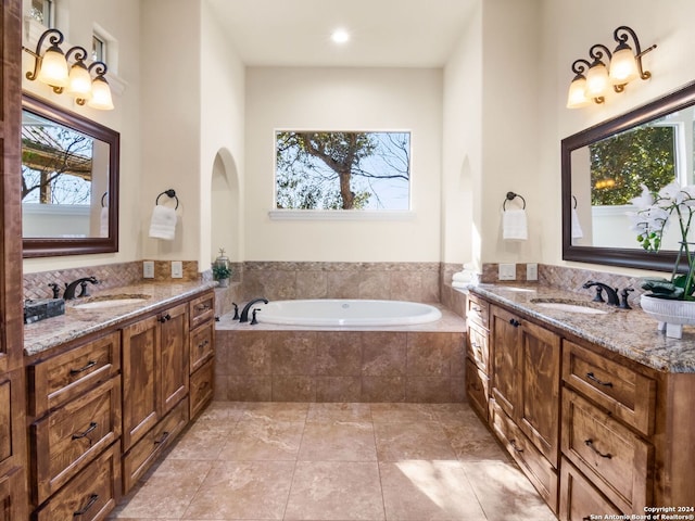 bathroom featuring tile patterned flooring, vanity, and tiled tub