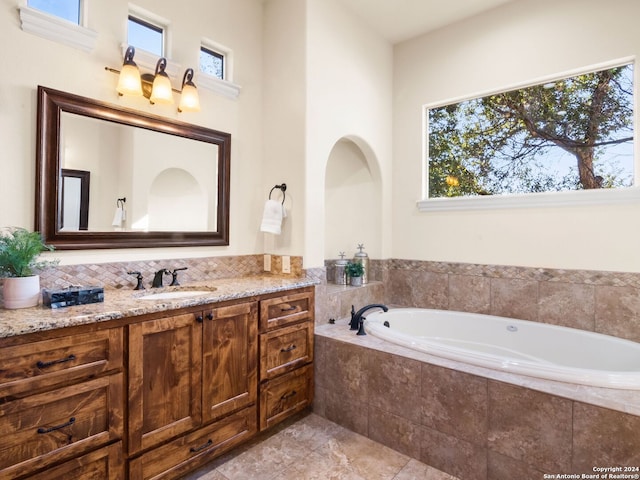 bathroom with tiled bath, vanity, and tile patterned floors