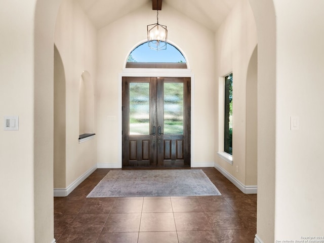 foyer featuring dark tile patterned flooring, french doors, beam ceiling, and high vaulted ceiling