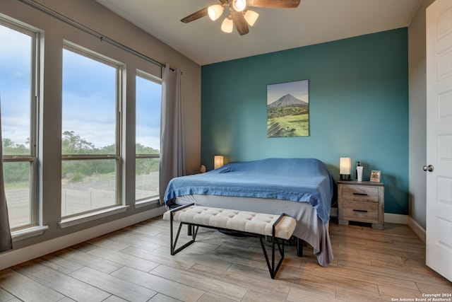 bedroom featuring light wood-type flooring, multiple windows, and ceiling fan