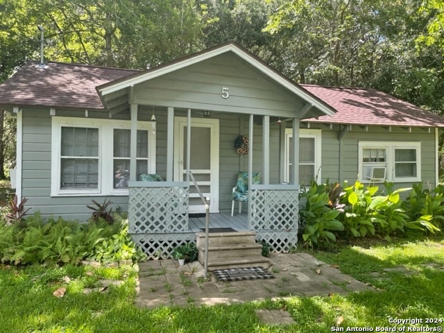 bungalow-style home featuring covered porch and cooling unit