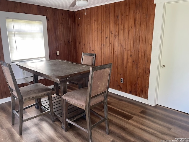 dining space featuring ceiling fan, dark hardwood / wood-style flooring, and wooden walls