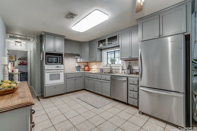 kitchen featuring stainless steel appliances, sink, gray cabinetry, and light tile patterned floors