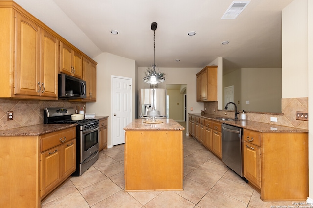 kitchen featuring sink, kitchen peninsula, light stone counters, appliances with stainless steel finishes, and a kitchen island