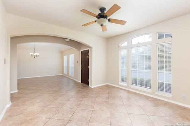 spare room featuring light tile patterned floors and ceiling fan with notable chandelier