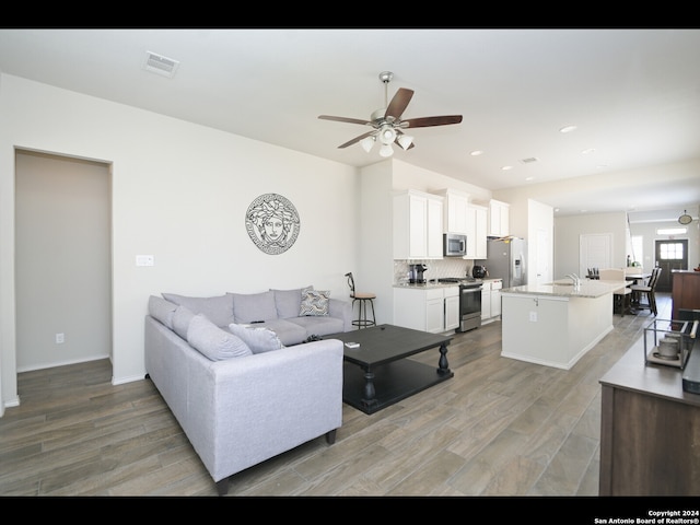 living room featuring ceiling fan, wood-type flooring, and sink