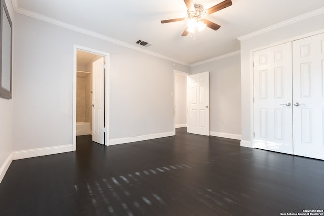 unfurnished bedroom with ornamental molding, ceiling fan, connected bathroom, a closet, and dark hardwood / wood-style flooring