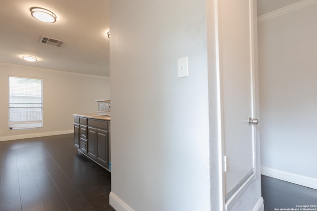 corridor with dark wood-type flooring and crown molding