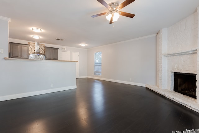 unfurnished living room with a fireplace, dark wood-type flooring, ceiling fan, and crown molding