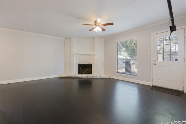 unfurnished living room featuring dark wood-type flooring, ceiling fan, a stone fireplace, and ornamental molding