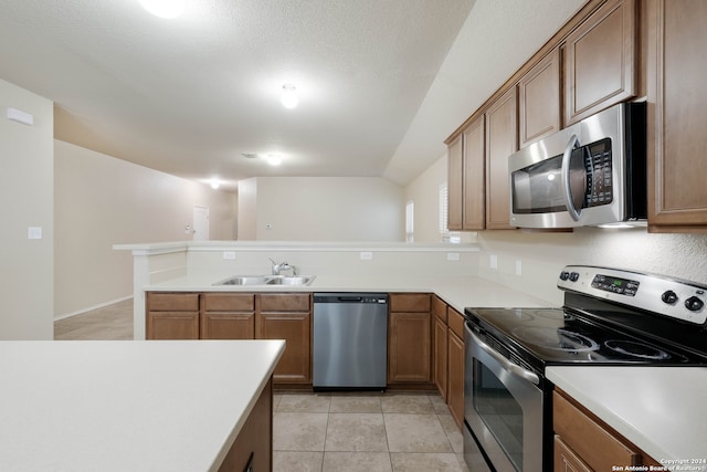 kitchen with stainless steel appliances, kitchen peninsula, a textured ceiling, sink, and light tile patterned floors