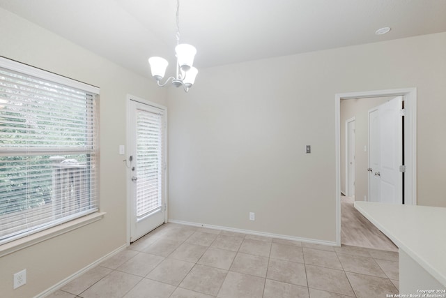 unfurnished dining area featuring a wealth of natural light, light tile patterned floors, and an inviting chandelier