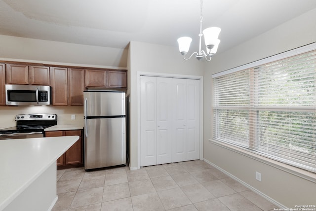 kitchen with pendant lighting, appliances with stainless steel finishes, an inviting chandelier, and light tile patterned flooring