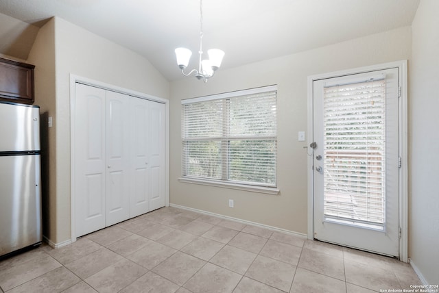 unfurnished dining area featuring light tile patterned floors, lofted ceiling, a healthy amount of sunlight, and an inviting chandelier